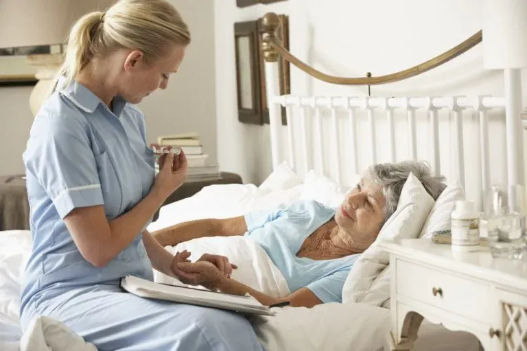 pielęgniarka siedzi przy leżącym pacjencie